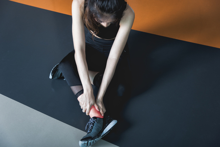 Young woman have ankle cramp in fitness exercise training in fitness gymの写真素材