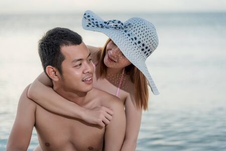 Happy Couple in love smiling - Man having his woman piggyback on his back on Thailand beachの写真素材