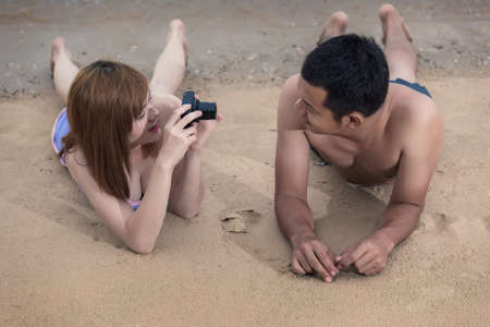 Woman taking photo picture of man smiling happy with camera of Thailand beachの写真素材