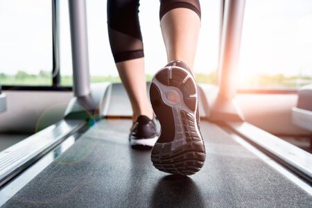 Close up sneakers Fitness girl running on treadmill, Woman with muscular legs in gymの写真素材