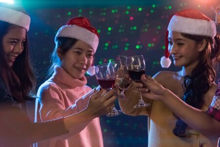 Group Asian young friends Enjoying Evening Drinks together party with Disco lights celebrating Christmas at dark home, Christmas or New Year conceptの写真素材