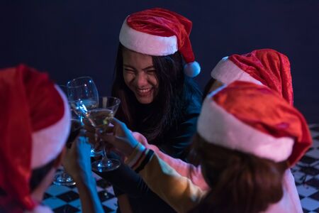 Group Asian young friends Enjoying Evening Drinks together party with Disco lights celebrating Christmas at dark home, Christmas or New Year conceptの写真素材