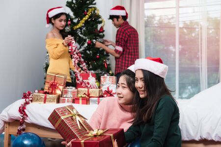 Group of friends celebrating showing gift box Christmas at home and Couple Decorating Christmas Treeの写真素材