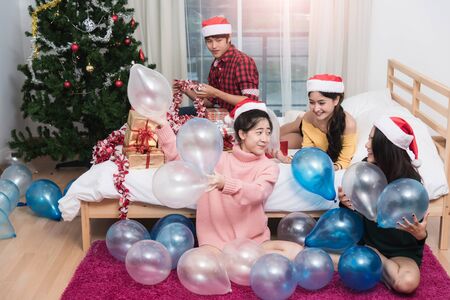 Group of friends celebrating Christmas at home throwing balloon up, Christmas or New Year conceptの写真素材