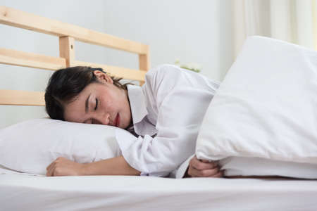 Beautiful young woman sleeping on white bed at bedroom in home