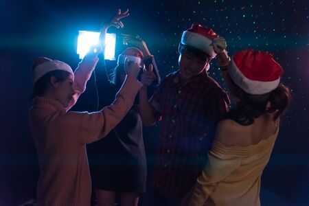 Group Asian young friends dancing Together party celebrating Christmas at dark home, Christmas or New Year conceptの写真素材