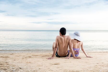 couple sitting together relaxing on paradise beach looking to horizonの写真素材