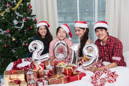Group of friends celebrating Christmas at home and showing 2019 up, Christmas or New Year conceptの写真素材