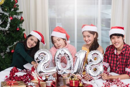 Group of friends celebrating Christmas at home and showing 2018 up, Christmas or New Year conceptの写真素材