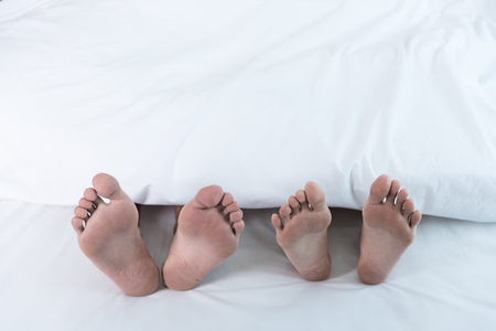 Closeup both feet couple lying on bed at home