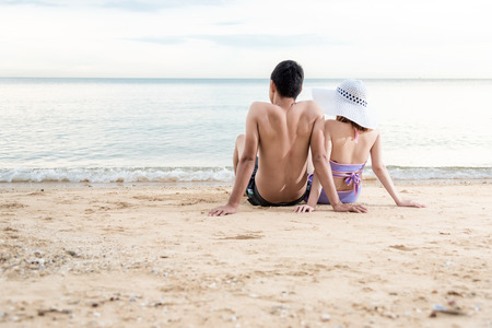 couple sitting together relaxing on paradise beach looking to horizonの写真素材