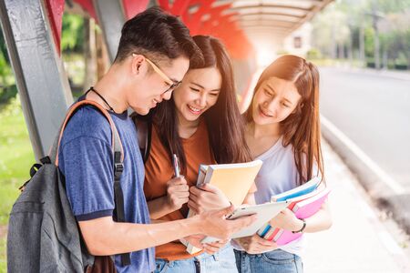 Group students studying outdoors consult together with tabletの写真素材