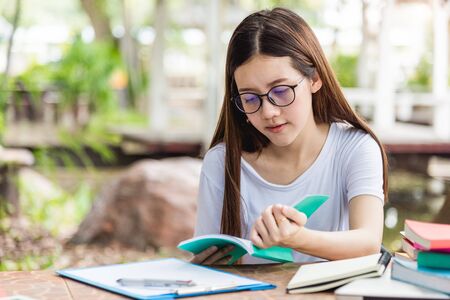 Young woman student studying holding an open book read sitting on tableの写真素材