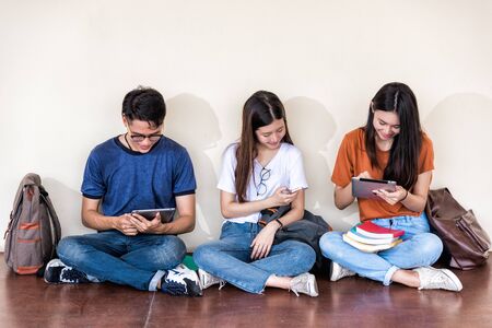 Man and girls friend classmates sitting useing with technology at university togetherのeditorial素材