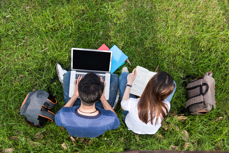Top view asian students sitting on grass with laptop and book consult learning togetherの写真素材