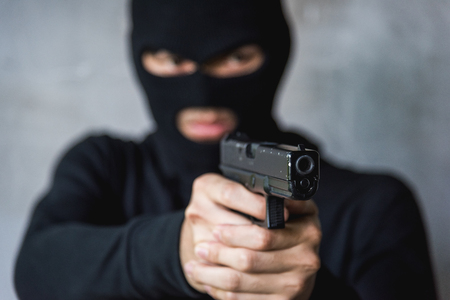 Masked robber with gun aiming, robber conceptの写真素材