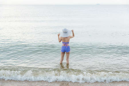 Outdoor summer portrait of young beautiful woman Helmeted looking to sea at tropical beach of Thailandの写真素材
