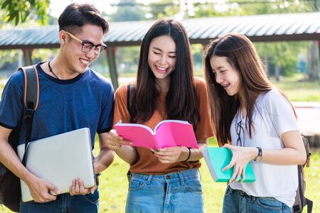 Happy group friends students standing in university read note book togetherの写真素材