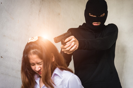 Man with pointing gun threaten woman, robber conceptの写真素材