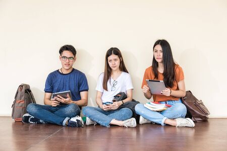 Man and girls friend classmates sitting useing with technology at university togetherの写真素材