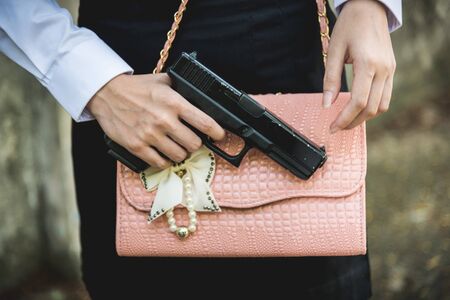 Young woman with concealed weapon gun in her small handbagの写真素材