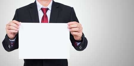 Businessman holding blank white paper for your text message on gray background