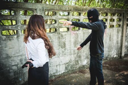 The black man robbers are about to criminal rob woman with a knife. But the woman fixes hide her gun in back of her.の写真素材