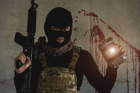 Heavily armed masked soldier holding time bomb, robber criminal concept