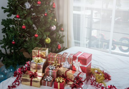 Many Christmas presents gift boxes on a table with Christmas tree, holidays, presents, new year and celebration conceptの写真素材