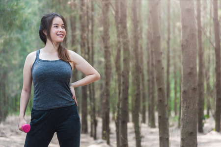 Sport young woman girl lifestyle relax holding fitness dumbbell workout in forest nature park with copy spaceの写真素材