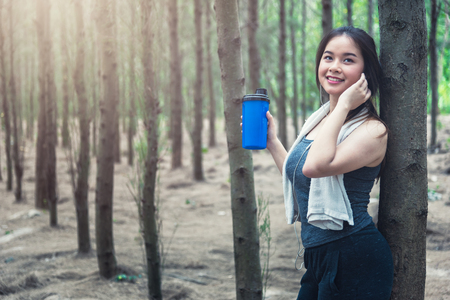 Sport beautiful young woman girl lifestyle exercise healthy drinking protein water after running workout in forest nature park with copy spaceの写真素材