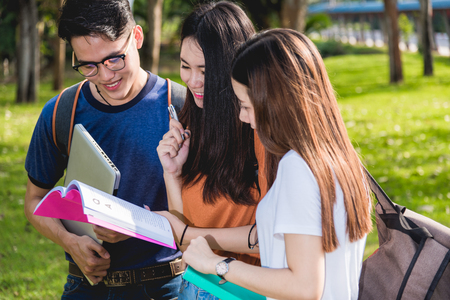 Happy group friends students standing in university read note book togetherの写真素材
