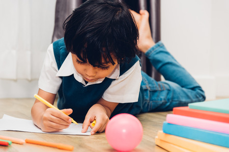 Happy child kid boy kindergarten drawing on peper teacher education at interior room homeの写真素材