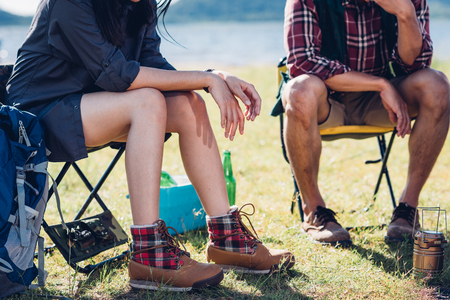 Young couple and friend sitting on chair discuss together camping on summer, focus legの写真素材