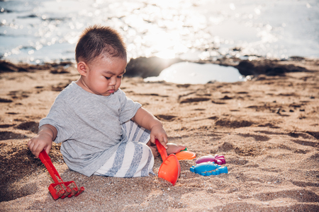 Baby boy playing sand on sea beach in vacation summerの写真素材