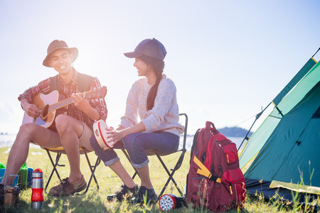 Happy group young friends in camping tent party having playing music fun together on outdoor holiday summerの写真素材