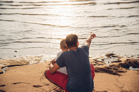 Baby boy son and father dad lifestyle happiness pointing to sea beach in vacation holidayの写真素材