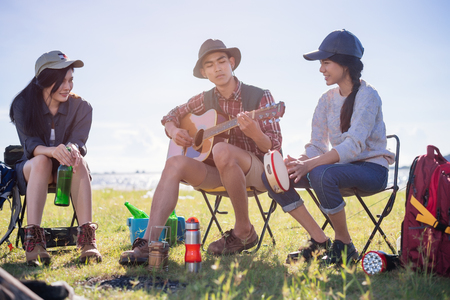 Happy group young friends in camping tent party having playing music fun together on outdoor holiday summerの写真素材