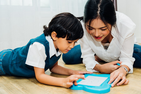 Family child kid boy son kindergarten and beautiful mother education teaching drawing together at interior room homeの写真素材