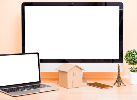 Front monitor, laptop computer blank screen and house model on desk table, construction architectural conceptの写真素材