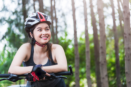 Beautiful young female woman helmet activity bicycle at forest on summer with copy spaceの写真素材