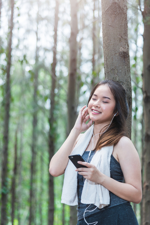Young sport woman lifestyle using smart phone after running at forest park copy spaceの写真素材