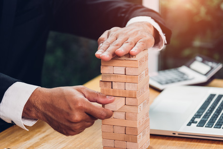 Business man strategy risk game pull tower block wood on desk office, management conceptの写真素材