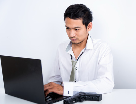 man and gun hacking laptop computer isolated on white backgroundの写真素材