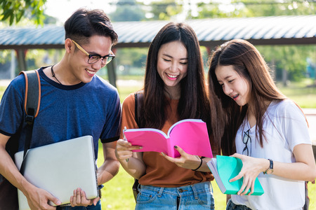Happy group friends students standing in university read note book togetherの写真素材