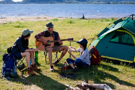 Happy group young friends in camping tent party having playing music fun together on outdoor holiday summerの写真素材
