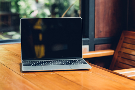 Laptop computer mockup with blank screen on desk in coffee shop.の写真素材