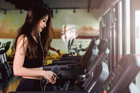 Woman lifestyle use technology smartphone music exercise on treadmill at fitness gym