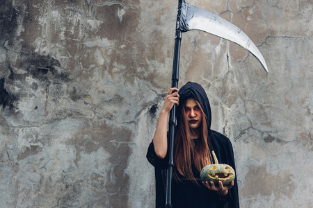 Portrait woman ghost demon she holding reaper and pumpkin, halloween conceptの写真素材