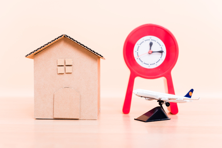 Cardboard paper model house, red clock and plane airplane, time travel businessの写真素材